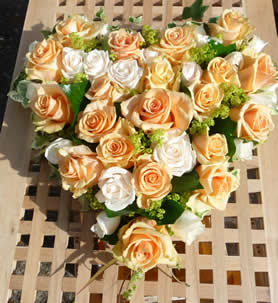 38cm solid heart of roses in gentle creams and pale apricots with foliage.